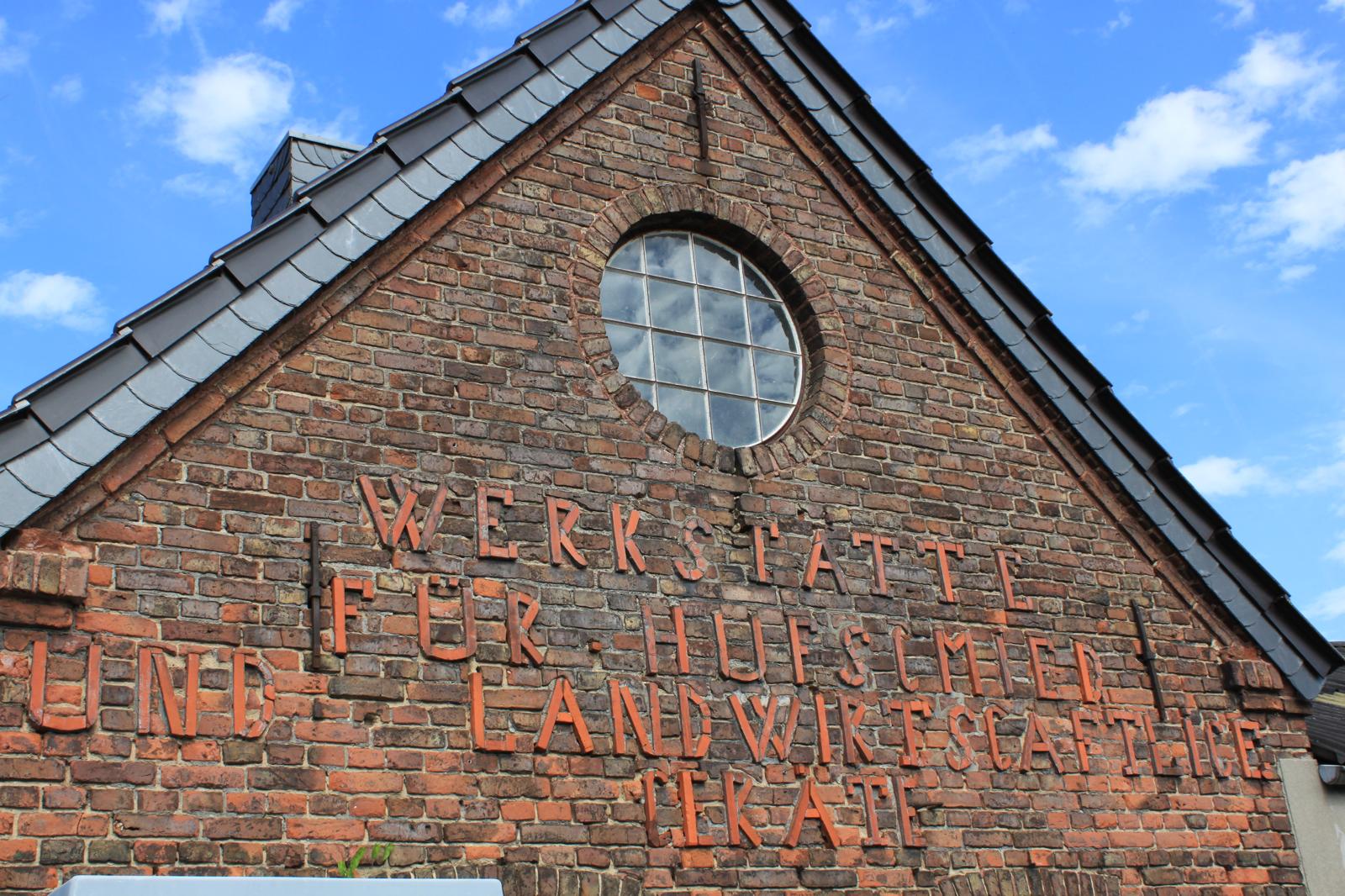 Giebel mit der Inschrift "Werkstätte für Hufschmied und landwirtschaftliche Geräte"