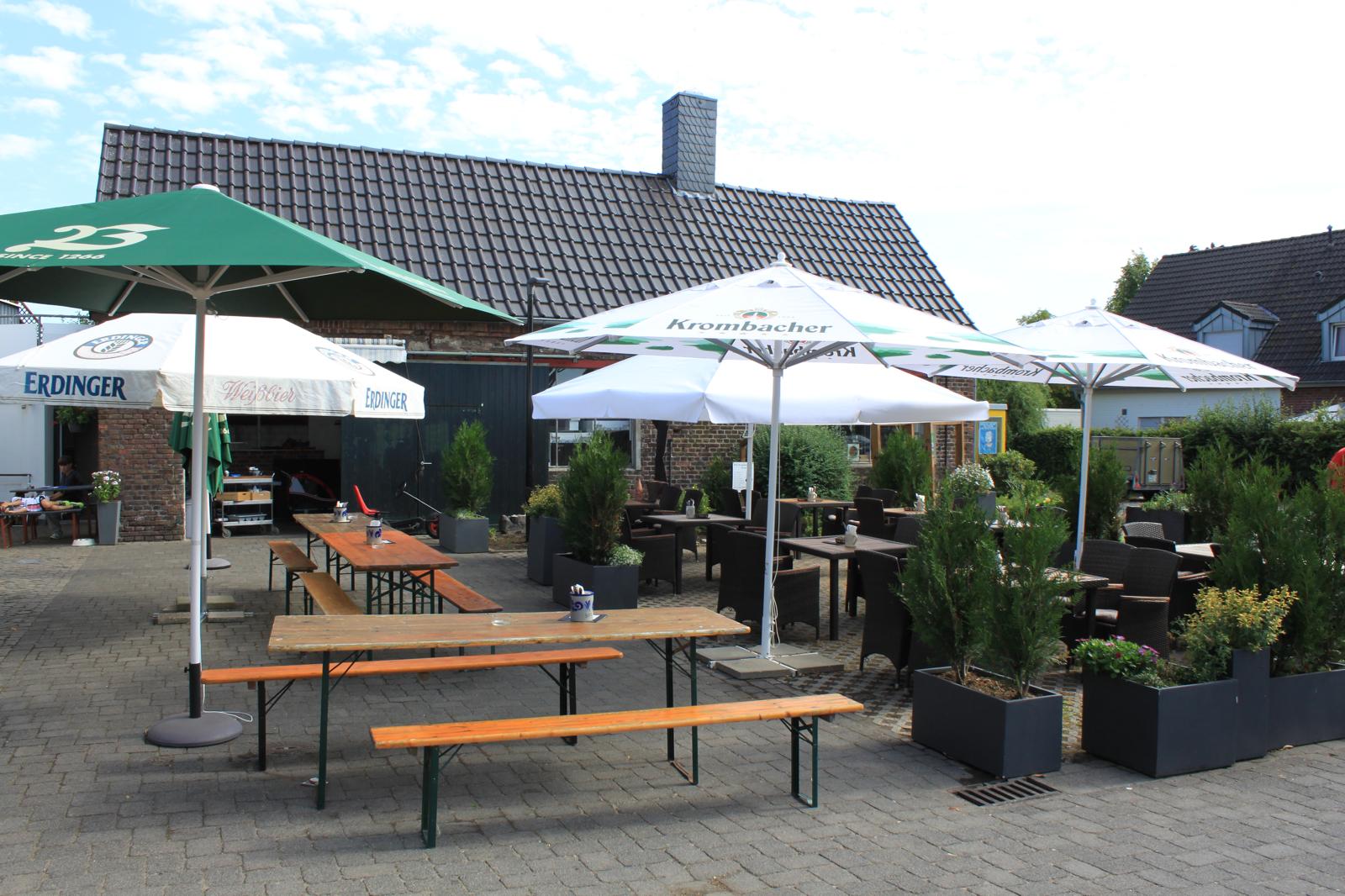 Biergarten mit Bierbänken, Sonnenschirmen und Loungemöbeln